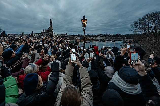 Výjev jako z pohádky. Pražský lampář rozsvěcí Karlův most, pro turisty je atrakce